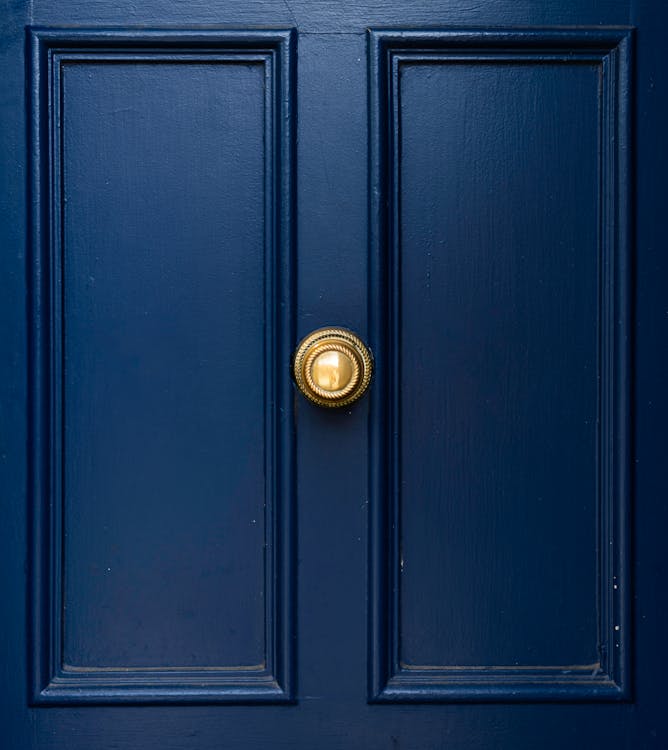 Close-up of a classic navy blue painted front door with a polished brass knob