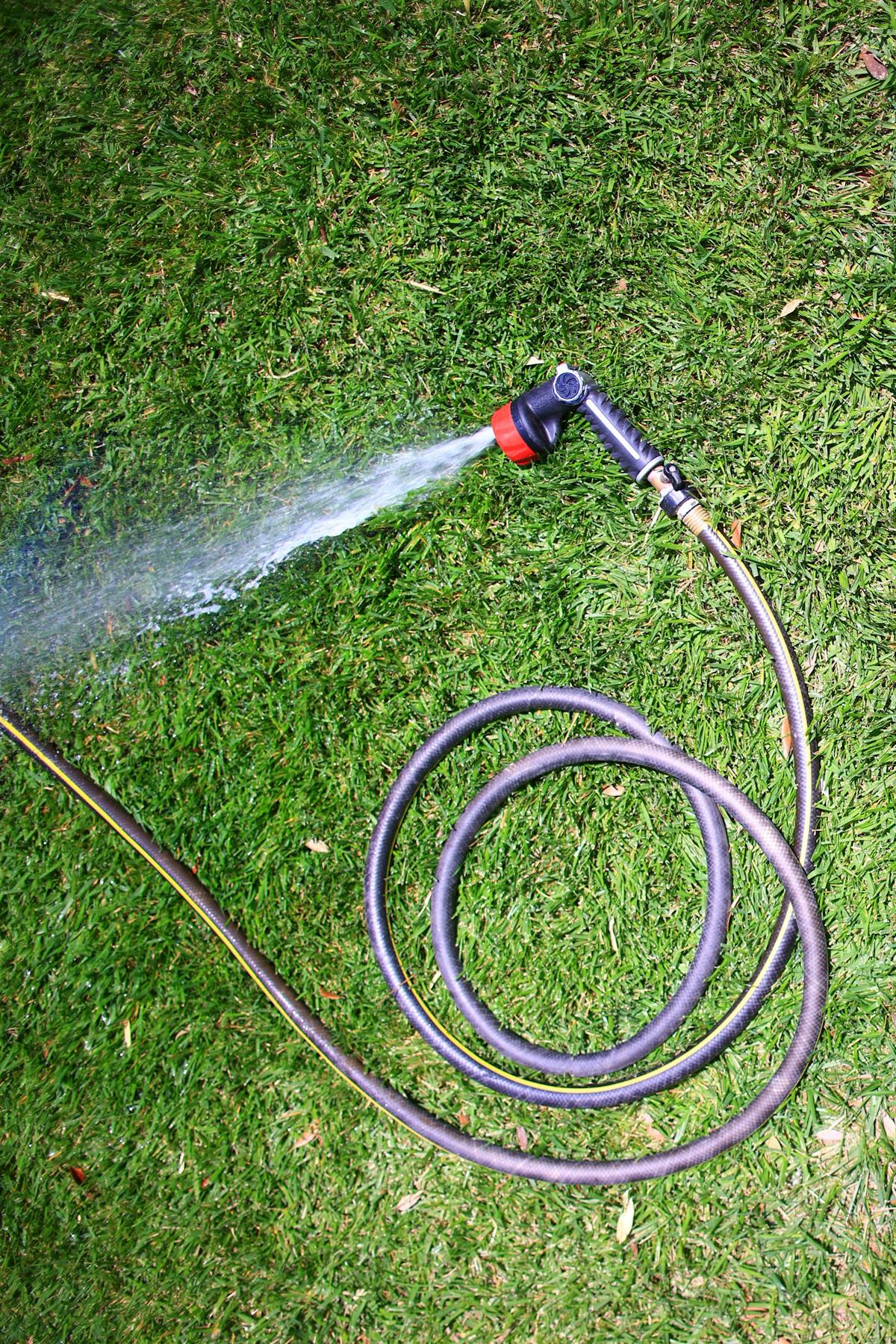 Garden hose coiled on grass with water spraying
