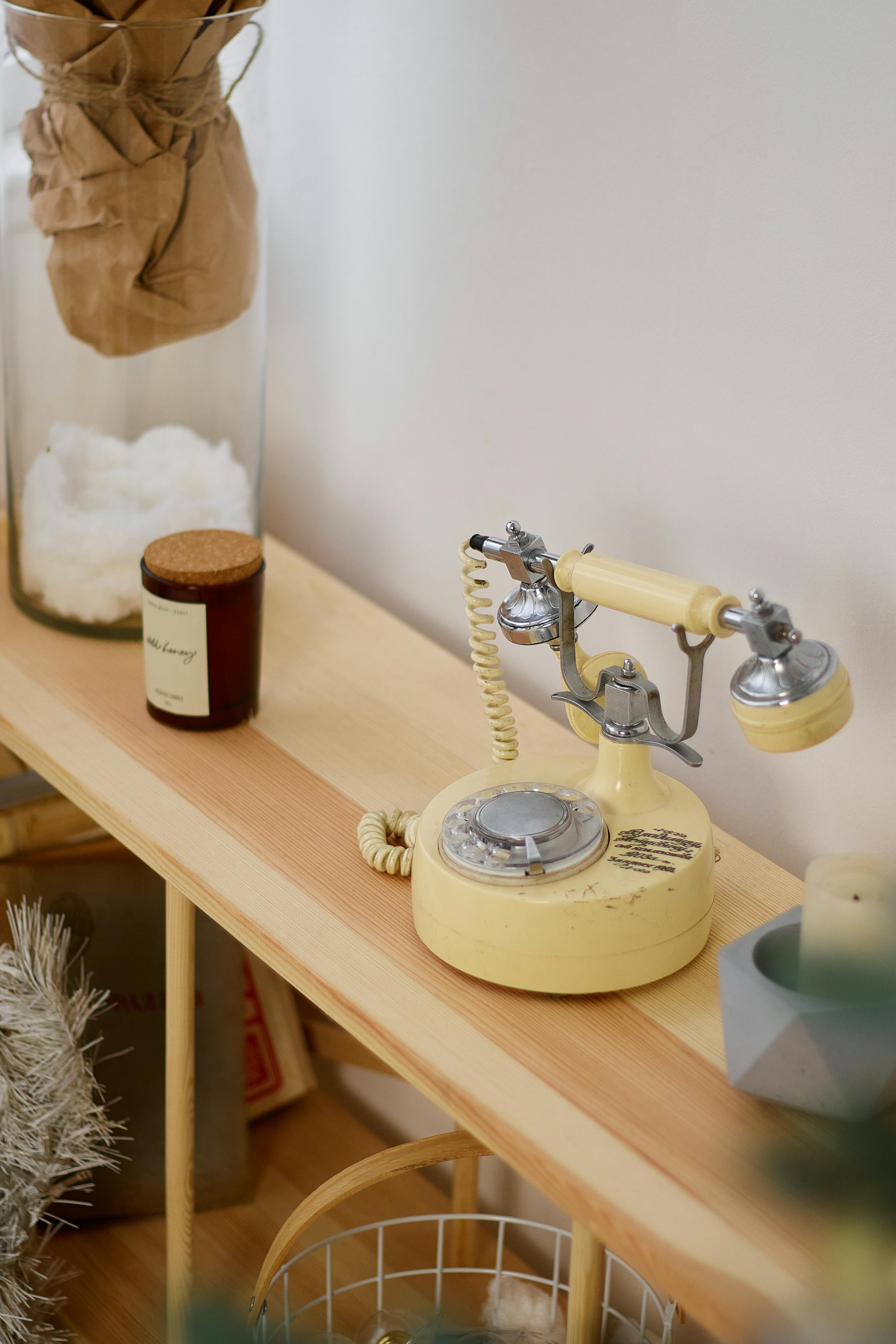 A vintage rotary telephone mounted in a built-in wall niche with a small shelf below