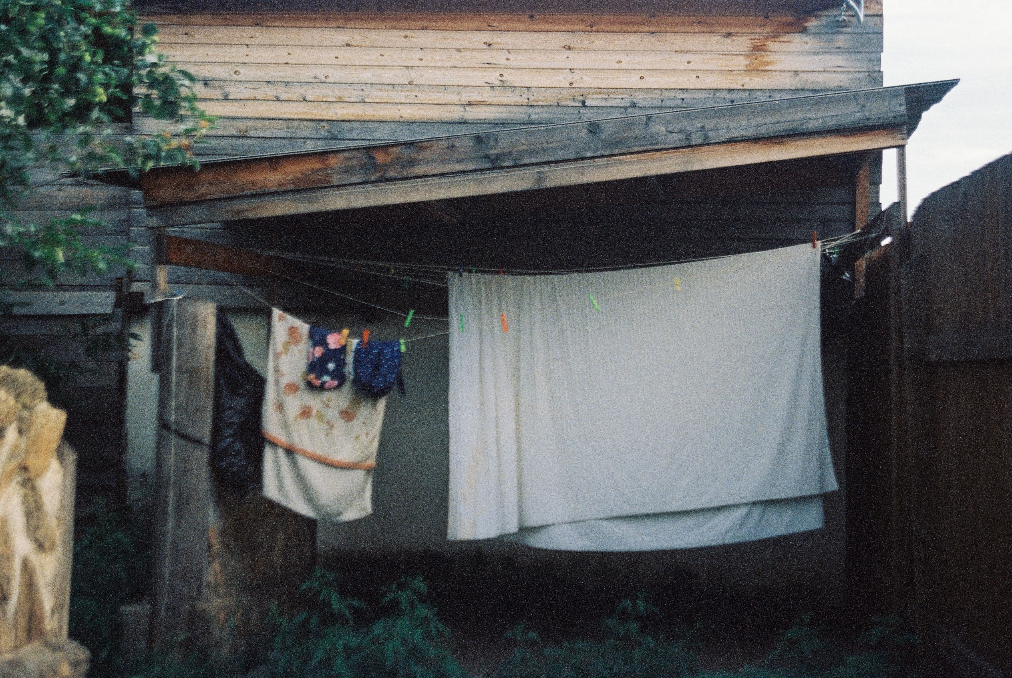 Clothes and towels drying on a backyard clothesline outside a wooden house