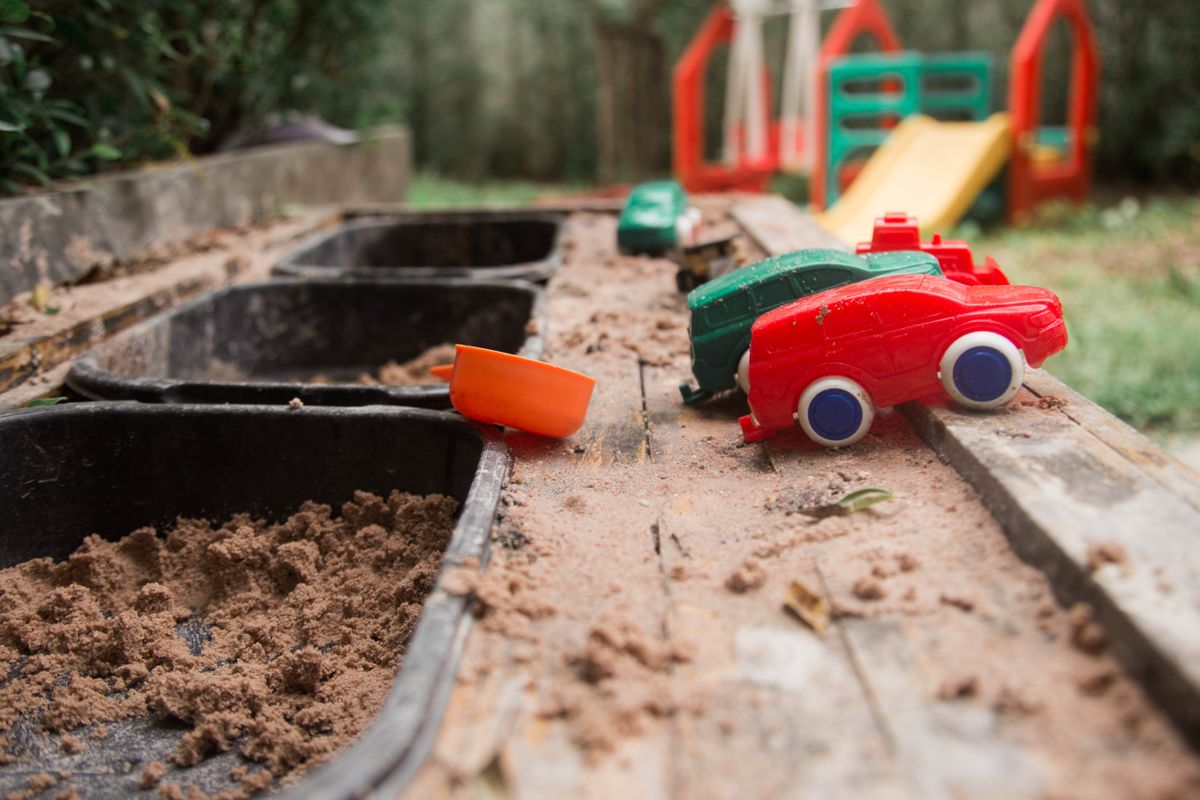 Colorful toy cars scattered in a wooden backyard sandbox