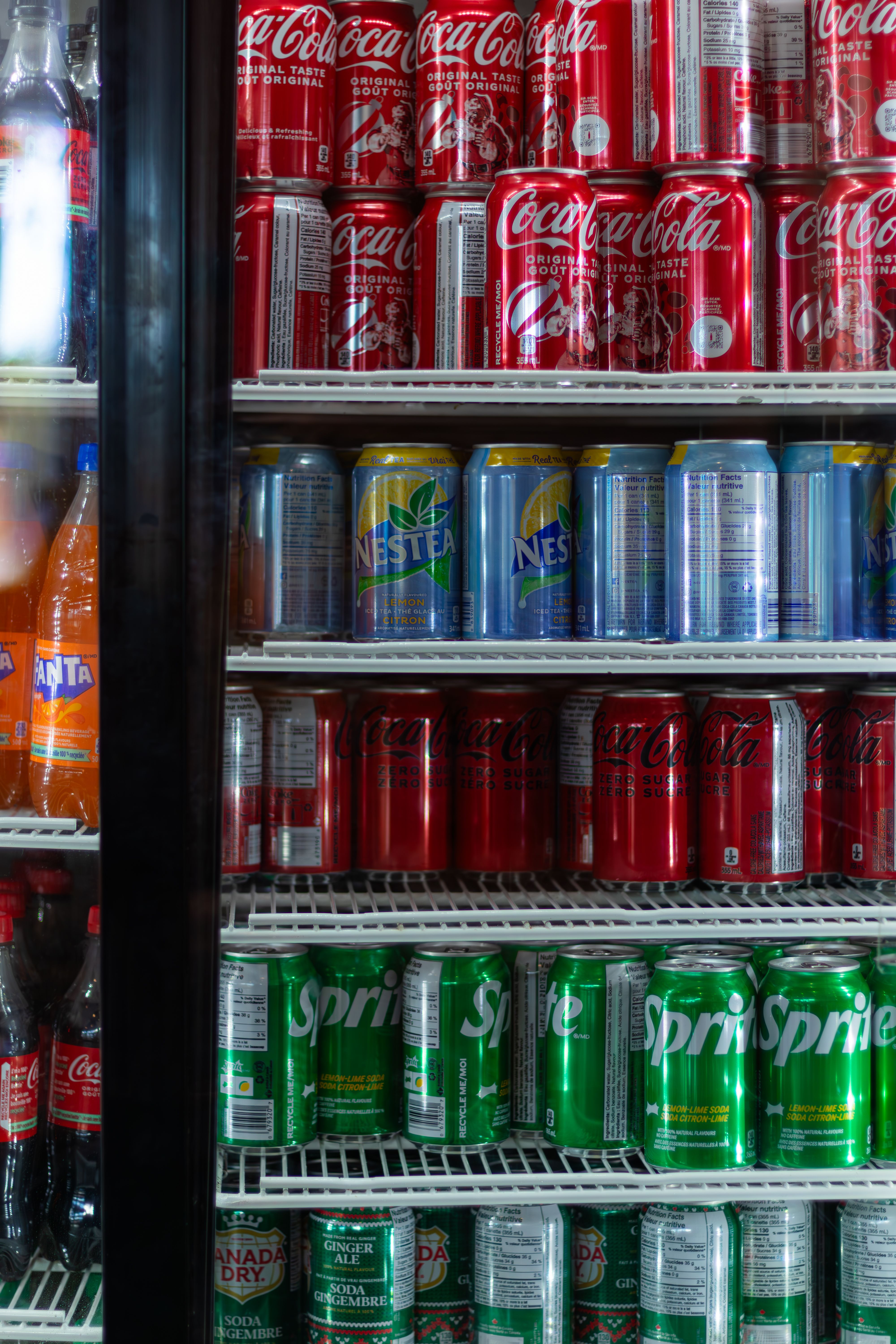Rows of assorted soda cans packed inside a refrigerator