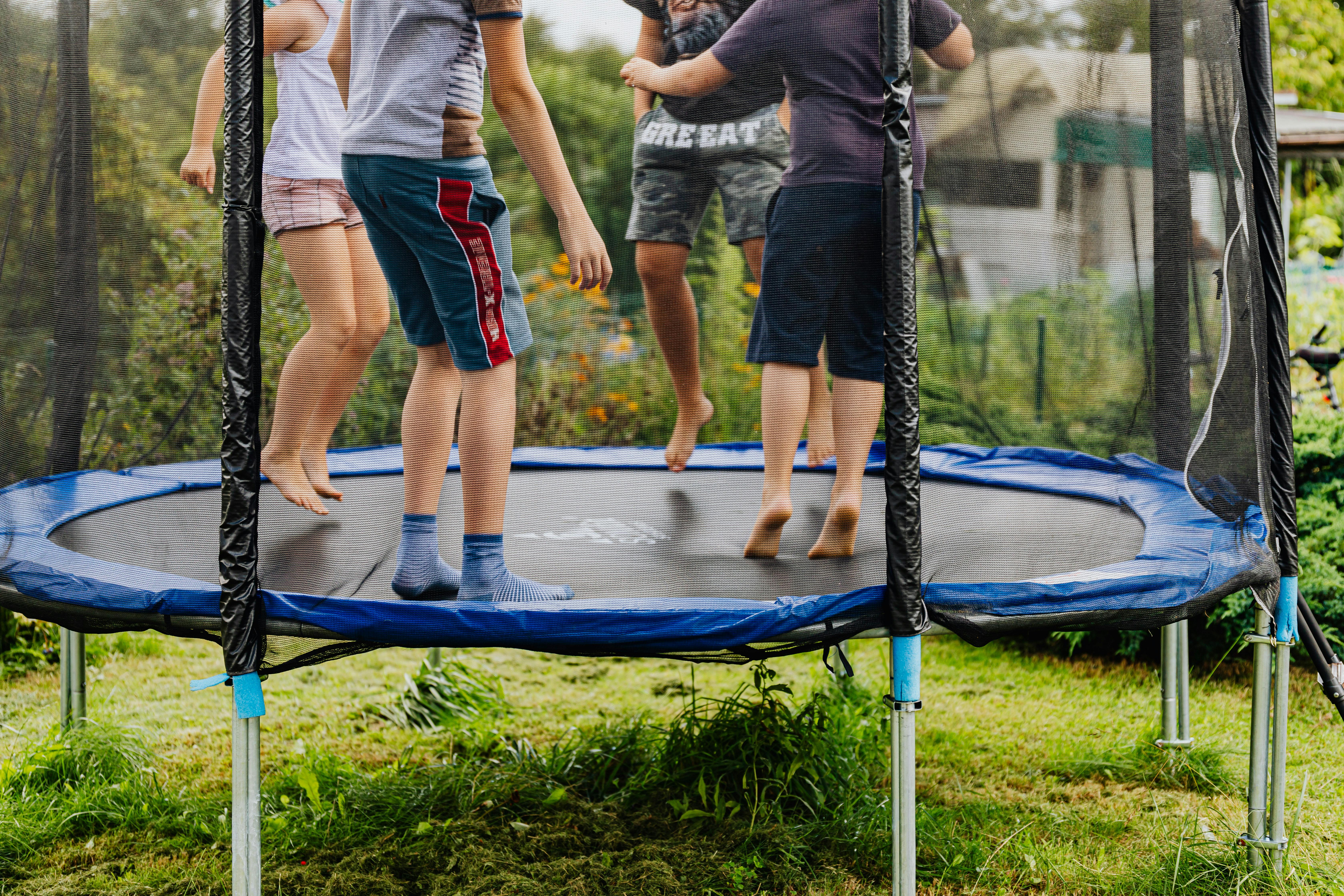 Kids jumping on a backyard trampoline on a summer lawn