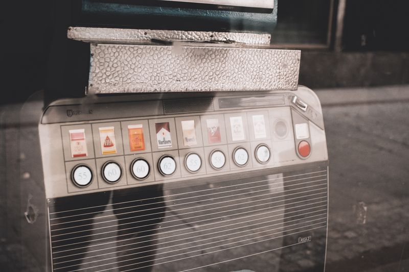 A retro coin-operated cigarette vending machine with pull knobs on a street