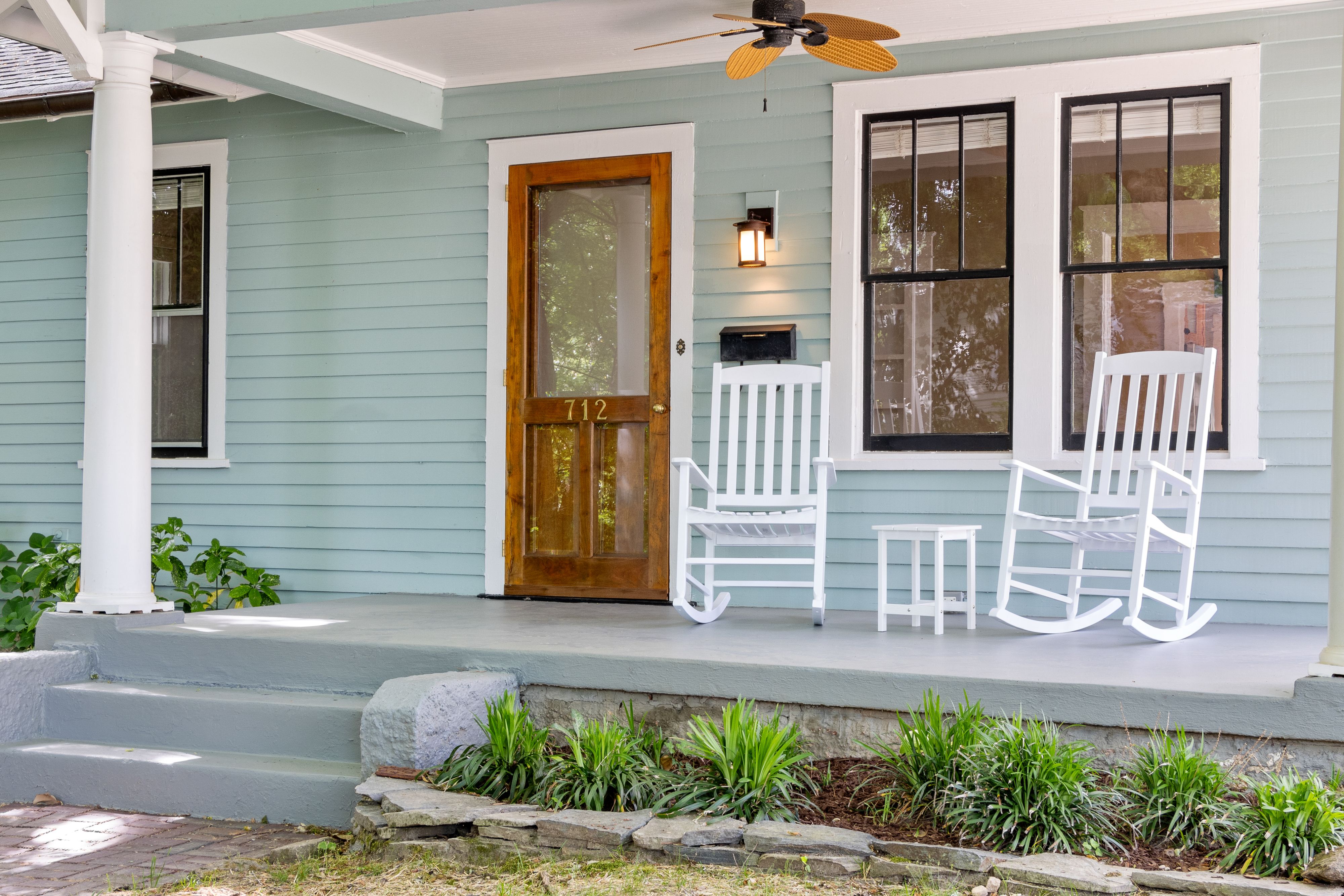 White rocking chairs on an inviting front porch with a wooden door