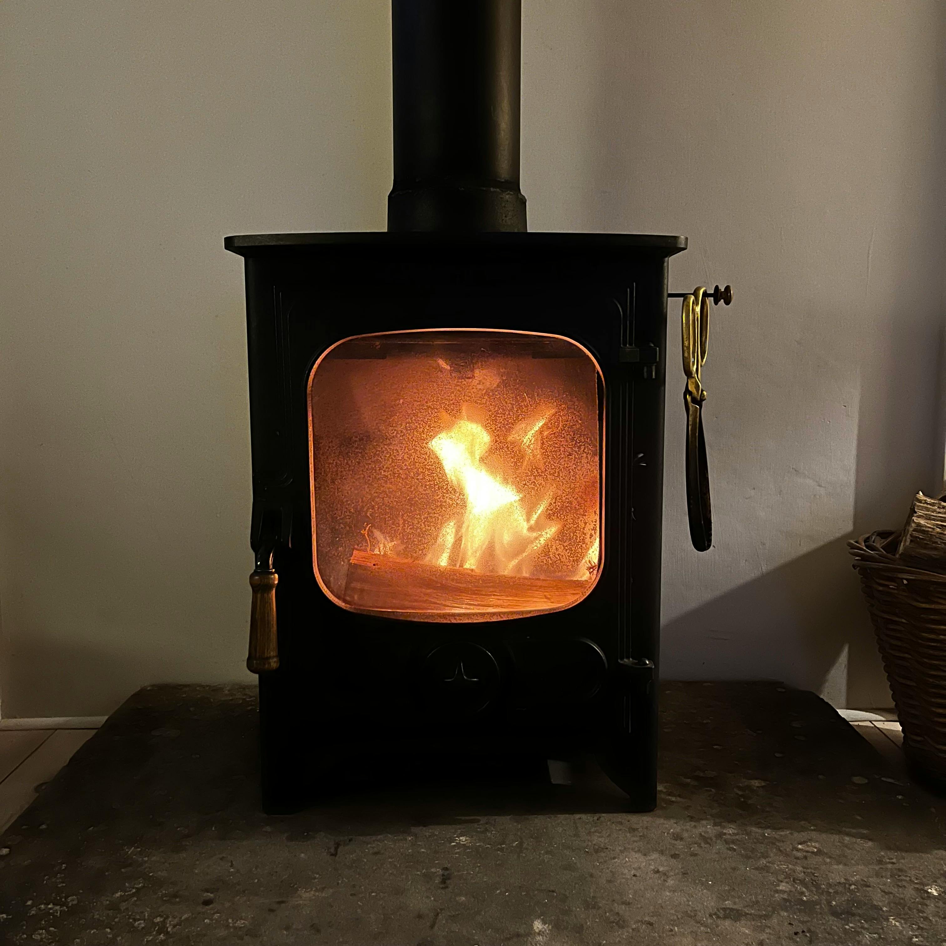 A cast iron wood stove with glowing fire behind glass