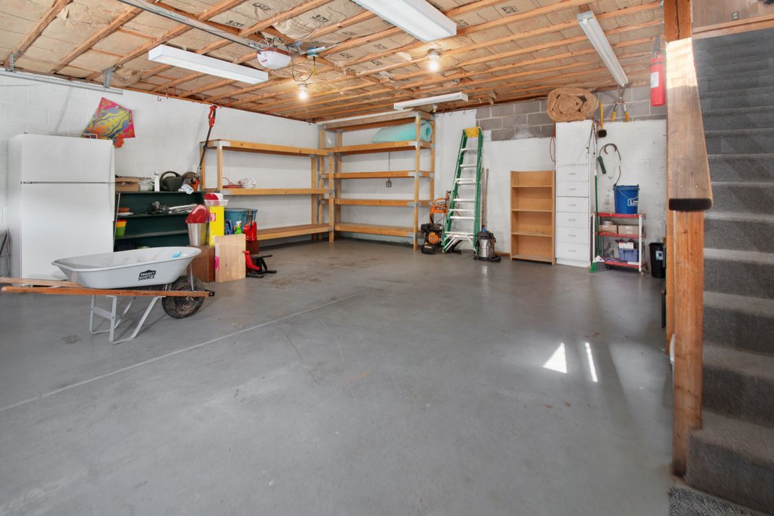 Spacious residential garage interior with swept concrete floor, organized wooden shelving, and open walkable space